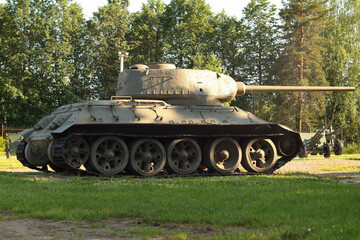 Old military tank under the trees, participated in the 2nd world war.