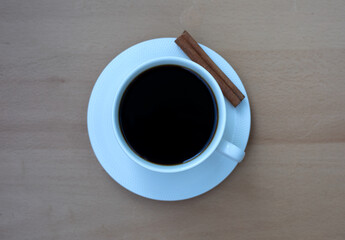 A white cup of coffee with a cinnamon stick on a table