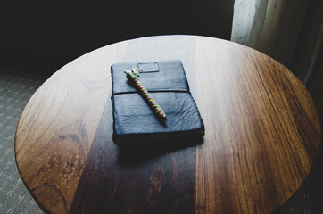 Handmade notebook with llama pen, on round wood table. 