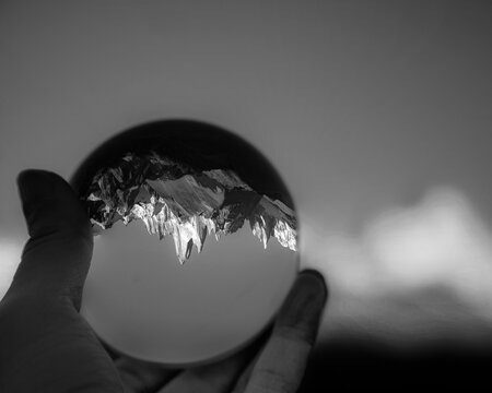 Black and white filter on a hand holding lens ball with a reflection of Patagonia Mount Fitz Roy.  