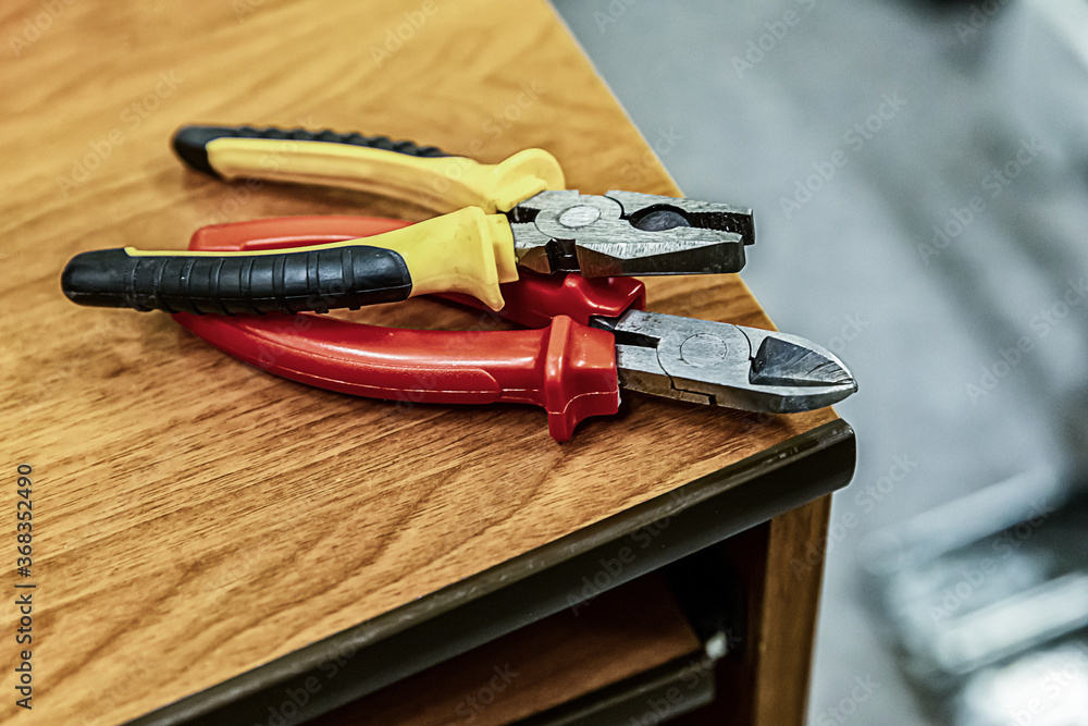 Wall mural pair pliers bright handles red yellow on a wooden table working engineer