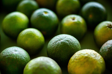 Close up of many green oranges fruits in a street shop. Top view. Fresh fruits and vegetables copy space background 