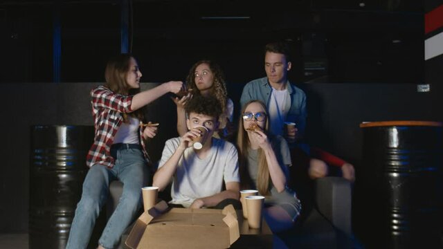 Students watching movie and eating pizza at night at home