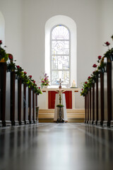 Blick durch den Mittelgang einer Kirche die f&uuml;r eine Hochzeit dekoriert ist.