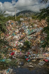 Waste and garbage dumped on the river bank. Water pollution and plastic garbage in the river