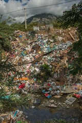 Waste and garbage dumped on the river bank. Water pollution and plastic garbage in the river