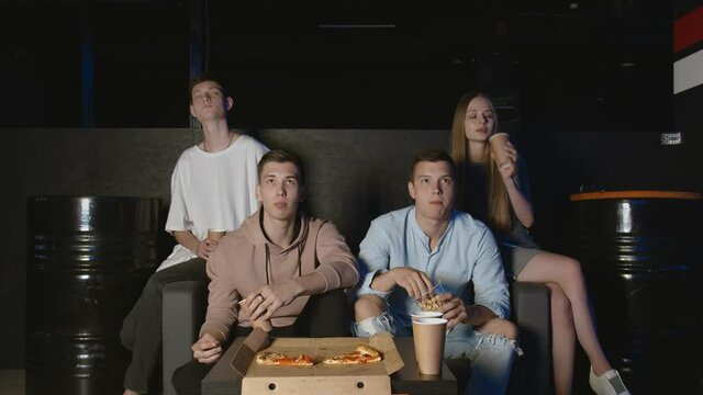 Best friends eating popcorn and pizza watching movie or tv show at home. People, friendship and lifestyle concept