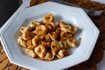 Capeletti in white dish on wooden table