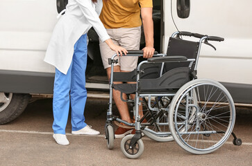 Doctor helping handicapped man to sit in car