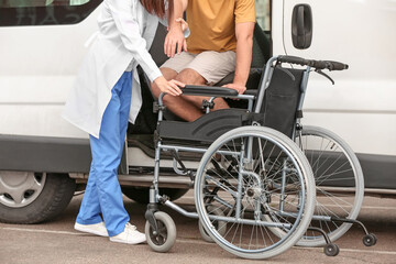 Doctor helping handicapped man to sit in car