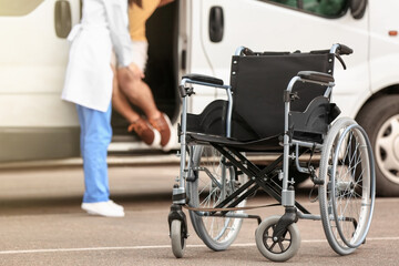 Doctor helping handicapped man to sit in car