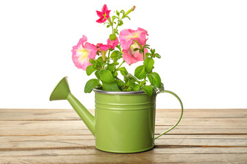Watering can with flowers on table against white background