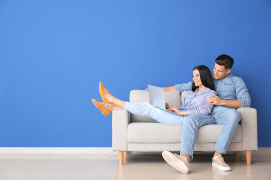 Young couple with laptop relaxing on sofa at home