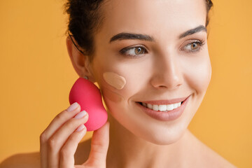 Beautiful young woman with foundation on her face against color background