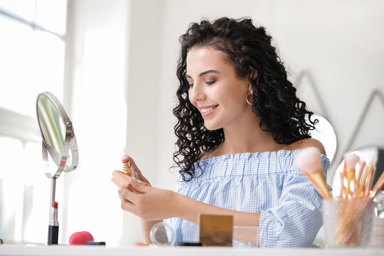 Beautiful Young Woman Applying Foundation At Home