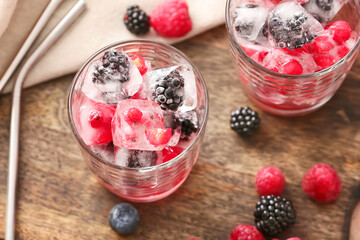 Glasses with ice and frozen berries on table