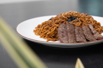 Korean traditional Jajjangmyeon black bean instant noodles with sliced beef on a plate.