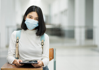 Portrait of a teenage college student wearing medical protective face mask with school backpack to protect from influenza virus, COVID-19 pandemic in college building