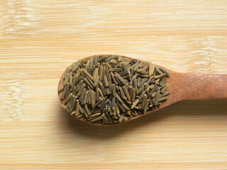 Brown and black color raw whole Bitter cumin seeds on wooden spoon