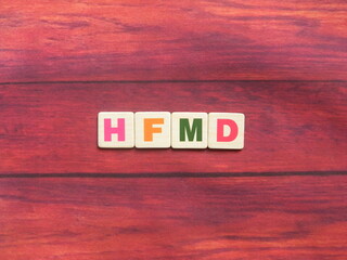 Abbreviation HFMD (Hand, Foot and Mouth Disease) on wood background