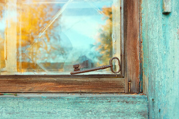 An old beautiful rusty key is lying on the window of an old house.
