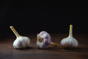 Horizontal view of three garlic heads on a black wooden background