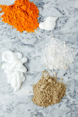 Creamy texture, salt, dry orange and light green powder pigmant for organic cosmetic on gray marble background. Texture. Close-up. Top view, curcuma powder ingredient