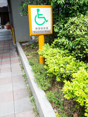 A wheelchair ramp with a white, yellow and green sign.