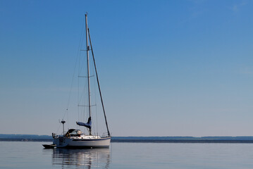 yacht with folded sail is anchored near the river bank at dawn