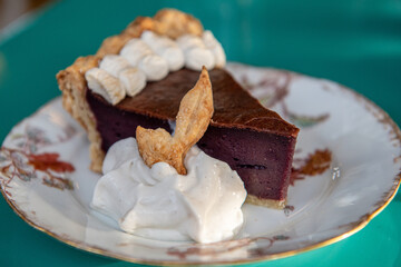Chocolate cake on porcelain plate, one slice on green table, decorated with white chattily 