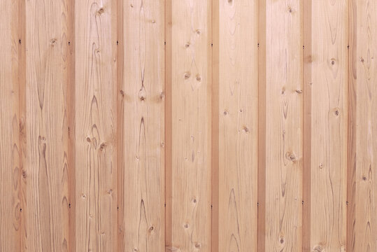 A close-up of a fragment of a wall made of vertical strug wooden planks. Horizontal orientation, front view. Selective focus. Wooden texture, background.