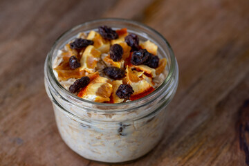 Dried oranges and raisins overnight oats on brown wooden board and a spoon, selective focus , viewed form an angle  - healthy eating concept with lots of copy-space