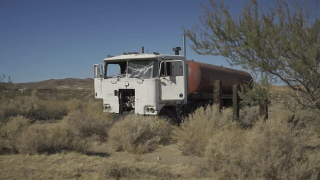 Front of abandoned truck wreck in the desert next to a highway.
