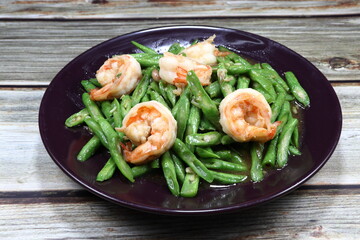 Traditional fried and stirred cutting green string bean with fresh peeled shrimp seasoning with soy sauce and pepper on the plate. Famous seafood and vegetable menu in Asia restaurant. 