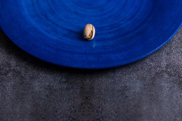 Fototapeta na wymiar Raw organic pistachio nuts presented on a blue plate
