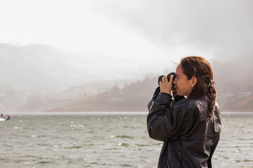 young woman taking photos at lake calima, colombia
