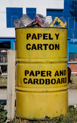 Yellow rustic trash bin for paper and cardboard overflowing of plastic bottles