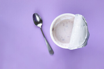 A pink yogurt with strawberry in an open plastic cup on pink background.