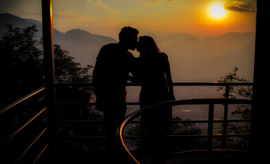 silueta de pareja besandose en lo alto de las montañas al atardecer