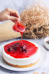 Ice box cheese cake with strawberry jam and a cup of coffee on the table.