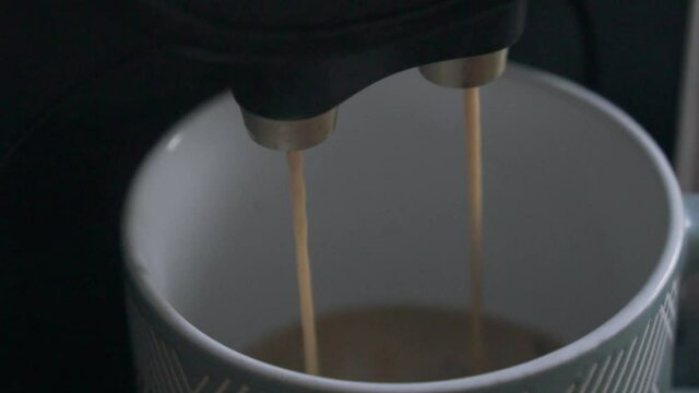 Coffee coming out of a coffee machine into a cup.
