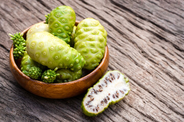 Noni fruits isolated on wood background .