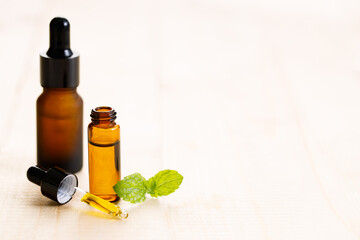 Peppermint essential oil with fresh mint leaves on wooden background