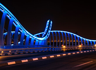 Illuminated Meydan bridge and view of Dubai city at dusk