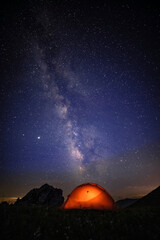 Fototapeta na wymiar The orange tent under the beautiful starry sky glows at night. The orange tent under the Milky way at night.