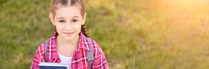 Young schoolgirl with backpack. Lifestyle going to classroom. Outdoor autumn park. Children learn smart. Street student. Happy preschool kid. Back to school