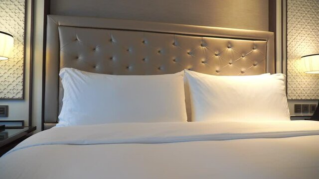 Pan across a hotel bed from bedstand to bedstand.