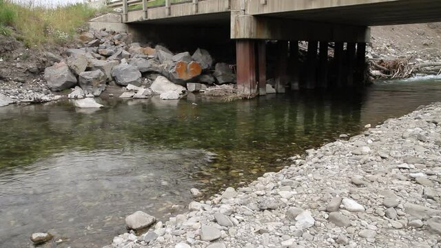 Wild and remote freestone trout creek crossed by bridge in the Rocky Mountain region of British Columbia