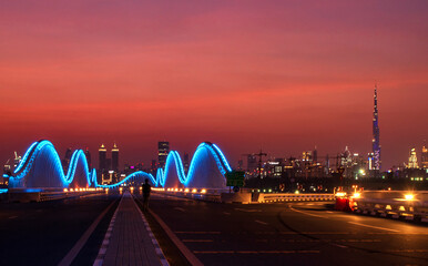 Illuminated Meydan bridge and view of Dubai city at dusk