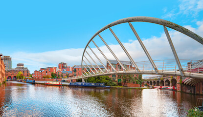Waterway canal area with a narrowboat on the foreground modern bridge, Castlefield district - Manchester, UK